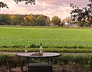 Prachtig uitzicht vanuit Vakantiehuis in Epe, Veluwe, Gelderland op groene velden en een kleurrijke zonsondergang.