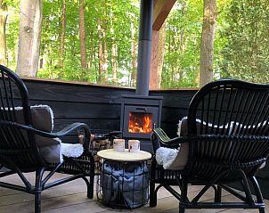 Cozy porch of Holiday Home in Epe in the Veluwe, Gelderland, with fireplace and views of the wooded landscape.