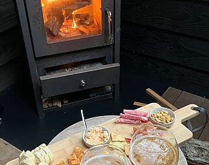 Cozy interior of Cottage in Epe, Veluwe with warm wood stove and drinks board, perfect for relaxation in Gelderland.