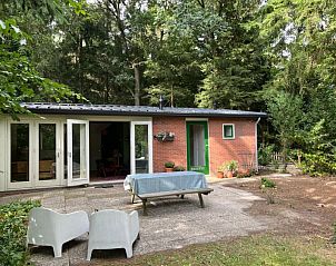 Boshuis Wissel vakantiehuis in Epe, Veluwe, met terras omgeven door groene natuur voor een serene ontsnapping.