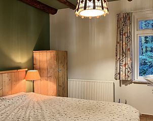 Gezellige slaapkamer in Boshuis Wissel, vakantiehuis in Epe op de Veluwe, met houten interieur en uitzicht op de omliggende natuur.