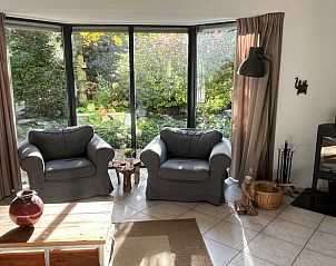 Cozy living room of Cottage in Epe, Veluwe, with comfortable chairs and views of the green garden, ideal for relaxation.