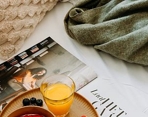 Relaxed breakfast at Holiday Home in Nunspeet, Veluwe, with fresh juice and a magazine in bed.