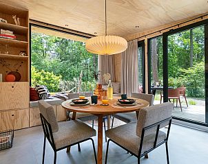 Gezellige eetruimte in TED Tiny House, vakantiehuis in Nunspeet, Veluwe, met zicht op groene natuur door grote ramen.