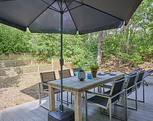 Outdoor area of De Linde in Nunspeet, Veluwe, with spacious table under a parasol and wooded area.