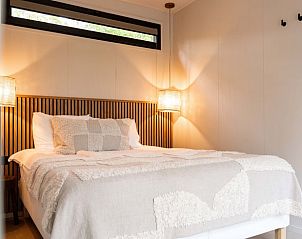 Sfeervolle slaapkamer in Huisje in Nunspeet, Veluwe, Gelderland, met comfortabel bed en warme verlichting voor een ontspannen verblijf.