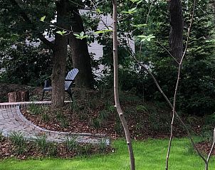 Quiet garden with seating area at Holiday home in Nunspeet, Veluwe, surrounded by greenery.