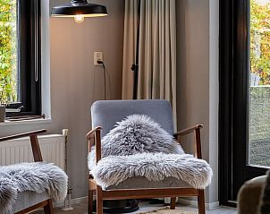 Comfortable chairs in living room of Holiday home in Nunspeet, Veluwe, overlooking garden.