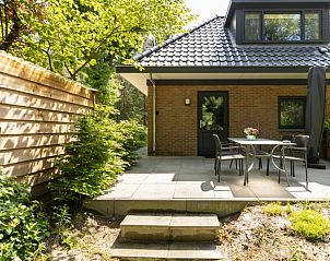 Terrace with dining table at Holiday home in Lunteren, Veluwe, Gelderland surrounded by greenery.