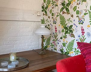 Sfeervolle hoek in Huisje in Rheden, Veluwe, met kleurrijk behang en vintage lamp op houten tafel.