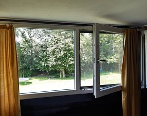 Uitzicht op de tuin vanuit een open raam in Huisje in Doornspijk, Veluwe, Gelderland.