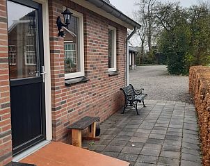 Terras met bankje bij de ingang van Huisje in Doornspijk, Veluwe, Gelderland.