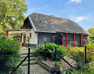 Zijaanzicht van het leukste vakantiehuisje in Wapenveld, Veluwe, omringd door groene natuur.