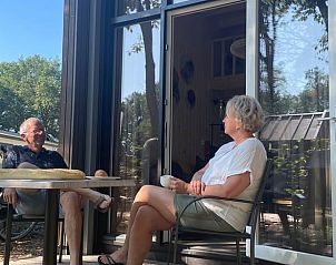 Guests enjoy coffee on the porch of Holiday Home in Lieren, Veluwe.