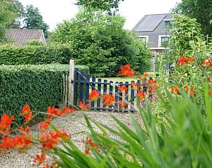 Toegangspoort tot Vakantiehuis in Laag Soeren, Veluwe met kleurrijke bloemen.