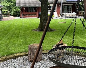 Buitenruimte met barbecue en schommel bij Boshuis Denne, vakantiehuis in Bennekom, Veluwe, Gelderland voor gezelligheid.