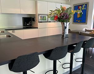 Keuken met barstoelen in Huisje in Bennekom, een vakantiehuis op de Veluwe, ideaal voor gezellige maaltijden.