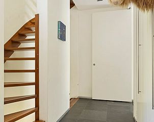 Elegante hal met houten trap in Huisje in Bennekom, een vakantiehuis op de Veluwe, Gelderland.