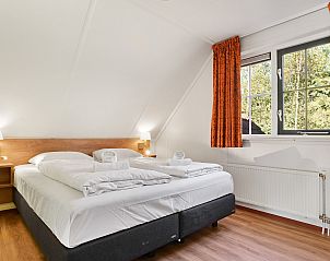 Tweepersoons slaapkamer in Coldenhove bungalow, Eerbeek, Veluwe met oranje accentmuur.