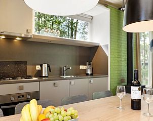 Gezellige eetkamer in Rabbit Hill kinderbungalow 8CK, Veluwe, met fruit en wijn op tafel voor een huiselijke sfeer.