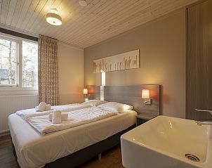 Gezellige woonkamer van Rabbit Hill 4-persoons kinderbungalow in Nieuw Milligen, Veluwe, met open haard en spelletjestafel.