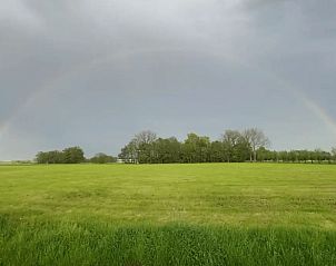Adembenemend uitzicht op het groene landschap bij Huisje in Nijkerk, vakantiehuis op de Veluwe in Gelderland, met een regenboog in de verte.