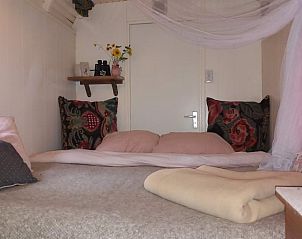 Knusse slaapkamer in Huisje in Nijkerk, vakantiehuis op de Veluwe, Gelderland. Gezellige sfeer met kleurrijke kussens en rustieke details.