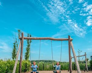 Kinderen op schommel in speeltuin bij Vakantiehuis Cube Magnifique 8, Nijkerk, Veluwe, Gelderland.