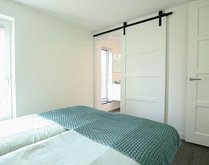 Slaapkamer met schuifdeur naar badkamer in Vakantiehuis Villa Meerzicht 10, Nijkerk, Veluwe, Gelderland.