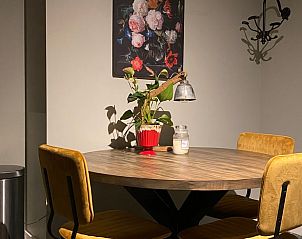 Stijlvolle eethoek in Vakantiehuisje in Kootwijkerbroek, Veluwe, met houten tafel en kleurrijke kunst aan de muur.