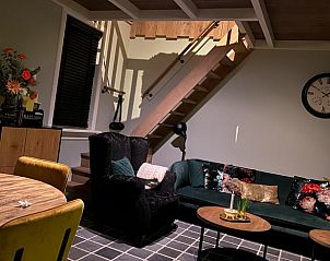 Moderne woonkamer in Vakantiehuisje in Kootwijkerbroek, Veluwe, met trap naar de bovenverdieping en sfeervolle verlichting.