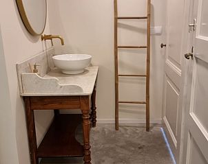 Stijlvolle wastafel en spiegel in de badkamer van Huisje in Klarenbeek, vakantiehuis in Gelderland.