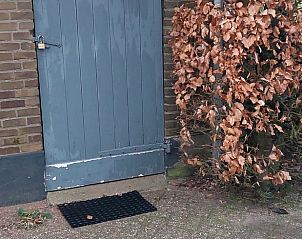 Auenansicht eines Ferienhauses in Klarenbeek, Veluwe, umgeben von grnen Struchern und einer rustikalen Backsteinfassade in Gelderland.