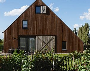 Huisje in Veessen, vakantiehuis op de Veluwe, met houten gevel en omringende bloementuin.
