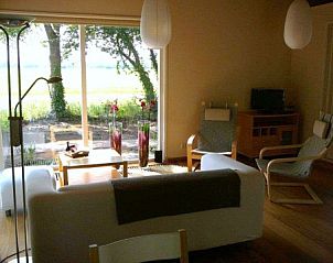 Gezellige woonkamer in Chalet Wildemansheerd, vakantiehuis in Schildwolde, met uitzicht op het Groningse landschap.