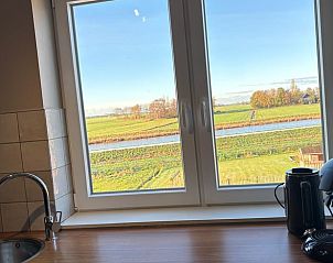 Uitzicht vanuit de keuken van Vakantiehuisje in Schildwolde, Groningen, met weidse velden en een rivier in Noordoost Groningen.