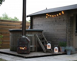 Buitensauna en hot tub in Robbenoort 121 Lauwersoog de Merel, vakantiehuis in Groningen met sfeerverlichting.