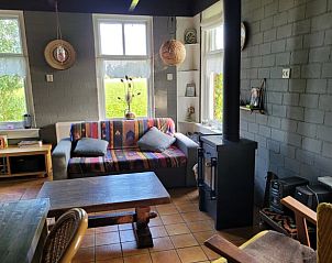 Gezellige woonkamer van Huisje in Uithuizen, vakantiehuis in Noordoost Groningen, met houtkachel en uitzicht op de groene omgeving.