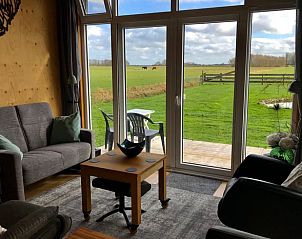 Sfeervolle woonkamer met terrasuitzicht in Vakantiehuis in Overschild, Groningen.