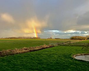 Regenboog boven groene velden bij Vakantiehuis in Overschild, Groningen.