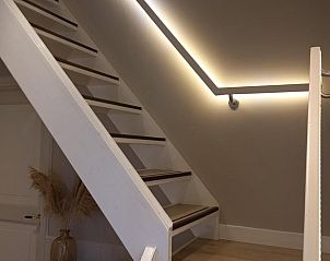 Houten trap met moderne verlichting in Vakantiehuisje in Leermens, Noordoost Groningen.