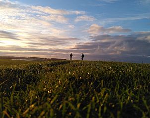 Uitzicht op weidse velden bij zonsondergang vanuit Vakantiehuis in Roodeschool, een serene vakantiewoning in Groningen.