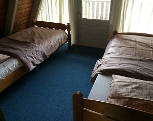 Tweepersoonskamer in vakantiehuis Robbenoort 29, Lauwersoog, Groningen met twee aparte bedden en een deur naar het balkon.