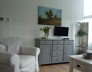 Gezellige woonkamer in Vakantiehuis in Ter Apel, met comfortabele bank en schilderij.