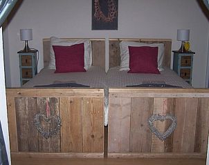 Sfeervolle slaapkamer in Huisje in Ter Apel, een vakantiehuis in Zuidoost Groningen met rustieke houten bedden en warme accenten.