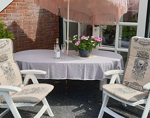 Zonnig terras met parasol bij Vakantiehuisje in Vriescheloo, ideaal voor ontspanning.