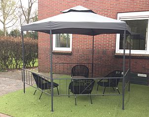 Gezellig terras met overkapping bij Huisje in Vriescheloo, een vakantiehuis in Zuidoost Groningen, ideaal voor ontspanning.