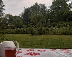 Theepot en kopje thee op tafel in de tuin van Vakantiehuis in Vriescheloo, een moment van rust in Groningen.
