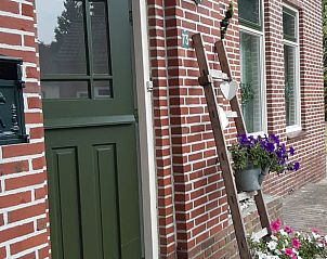 Charmante voordeur van Vakantiehuis in Vriescheloo met bloeiende planten in Zuidoost Groningen.