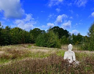 Serene tuin met Boeddhabeeld bij Vakantiehuis in Bellingwolde, omgeven door natuur.